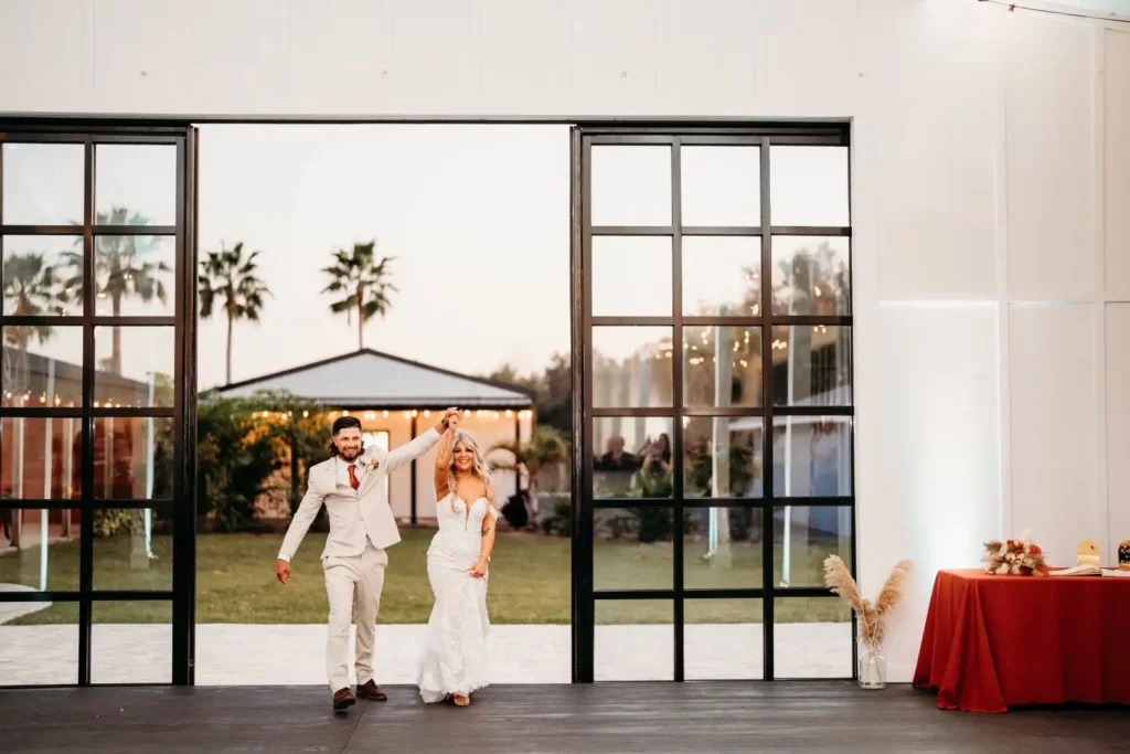 A bride and groom standing in front of a large glass door.